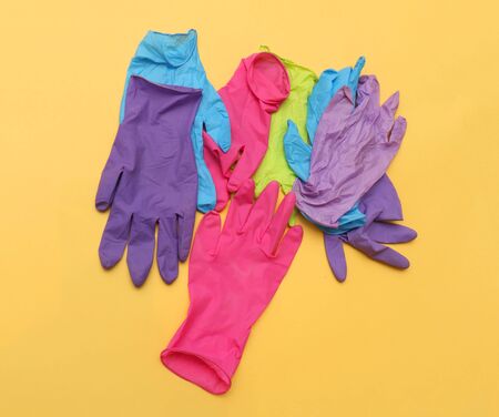 Colorful rubber latex medical gloves pile on yellow backgroundの写真素材