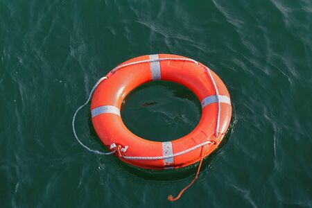Orange circle lifebuoy floating on sea water surface