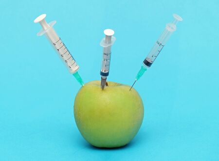 Green apple with injected syringe needles illustrating food modification industryの写真素材