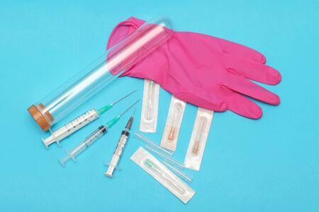 Pink surgical latex glove with glass test tube and syringes and needlesの写真素材