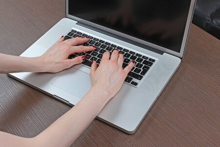 Female hands typing on modern laptop keyboard with empty screenの写真素材