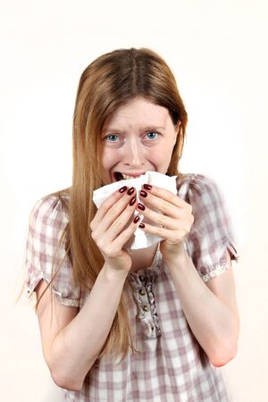 Young woman with sad face expression crying and holding facial tissue on her faceの写真素材