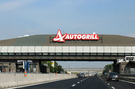 Milan, Italy - June 15, 2019: Highway on the way to Milan with cars on both sides of freeway and Autogrill restaurant with logo across on overlay bridge.のeditorial素材