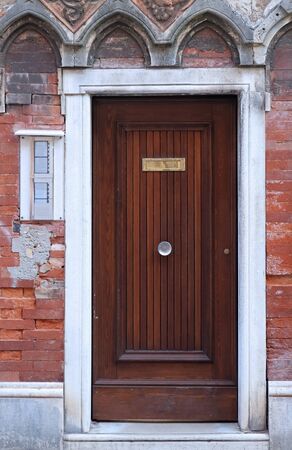 Closed retro wooden entrance door on dirty brick wall house facadeの写真素材