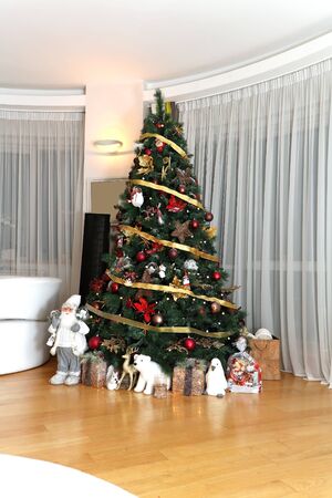 Tall decorative Christmas tree in modern room with gifts underneathの写真素材