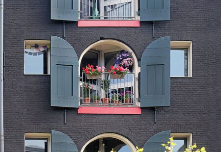 Open window on retro house in Amsterdam with colorful flowers decorの写真素材
