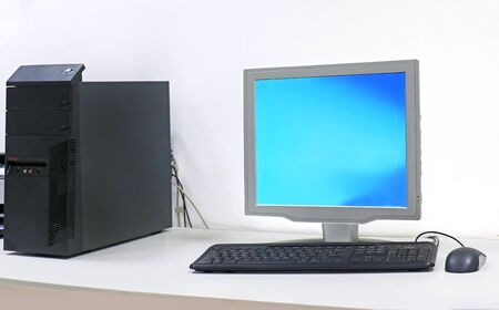 Computer with blue screen and keyboard inside modern room interiorの写真素材