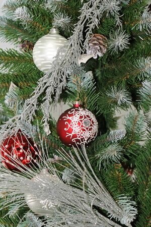 Festive bulb ornaments on Christmas tree covered with snowの写真素材