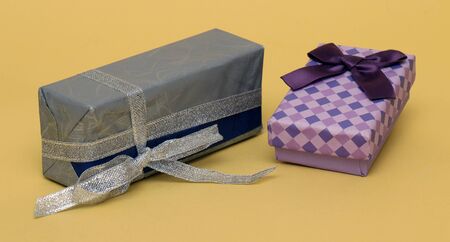 Beautiful colorful gift boxes with bows and silver glitter ribbon on yellow background