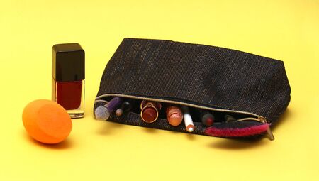 Make up lipsticks and eyeshadows inside cosmetic case on yellow backgroundの写真素材