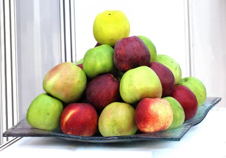 Fresh organic colorful apples fruit pile on glass plateの写真素材