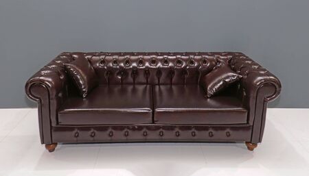 Retro chesterfield style glossy leather sofa inside empty interiorの写真素材