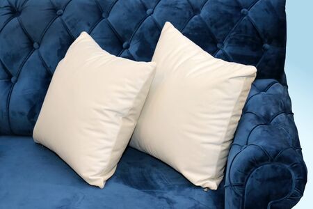 Two white textile pillows in corner of retro blue couchの写真素材