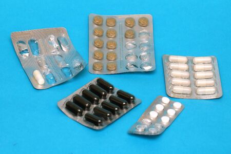 Prescription drugs and vitamins in silver blisters on blue backgroundの写真素材