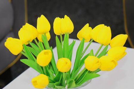 Bright yellow tulip flowers inside vase on interior tableの写真素材