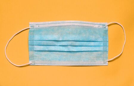 Surgical medical face mask on yellow background