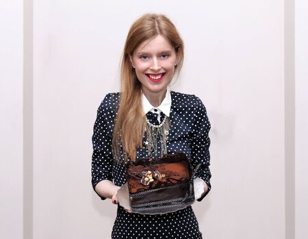 Smiling young woman in a party holding chocolate cakeの写真素材