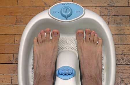 Male feet inside plastic pedicure bathtub getting ready for treatmentの写真素材