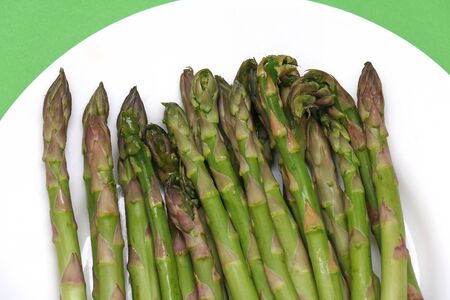 Fresh raw organic green asparagus vegetable on white plateの写真素材