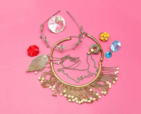 Shiny gold jewelry with colorful diamonds on pink backgroundの写真素材