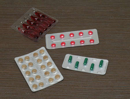 Injection vials and colorful pills in silver blisters