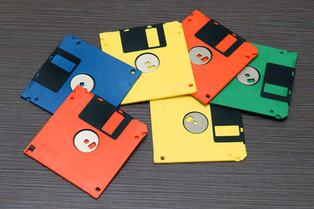 Stack of retro colorful floppy disks on wooden tableの写真素材