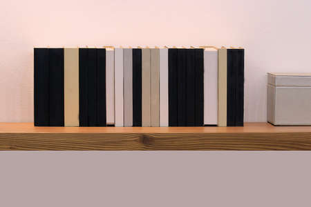 Old vintage hardcover books in row on brown wooden shelfの写真素材