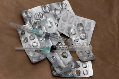 Pile of used empty silver blisters pills and syringes with needlesの写真素材