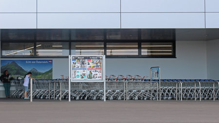 Vienna, Austria - July 10, 2015:  Exterior of famous large German  discount grocery store Lidl with people waiting to take a shopping  trolley to go inside near designer outlet Parndorf in Viennaのeditorial素材