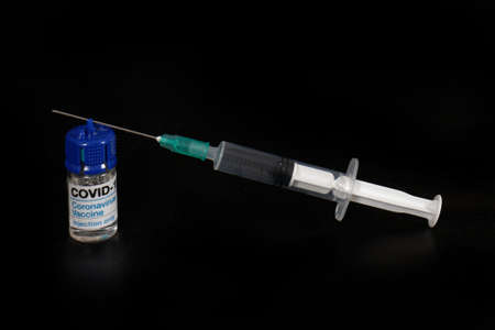 Covid-19 vaccine vial and syringe with needle on black backgroundの写真素材