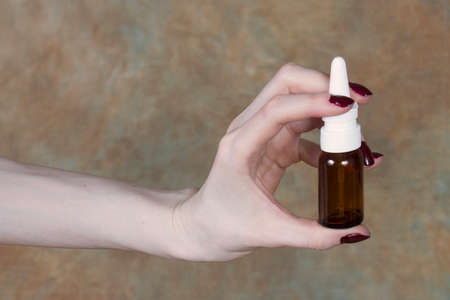 Female hand holding nasal spray pump in glass bottleの写真素材