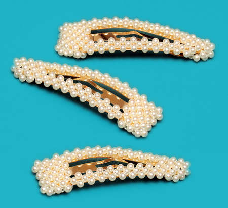 Gold pearl fashion style hair clips isolated on blue backgroundの写真素材