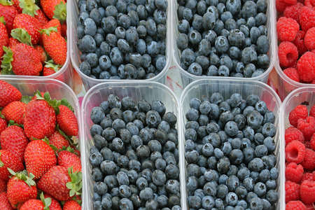 Fresh organic raw berries fruits in plastic containers sold on marketの写真素材