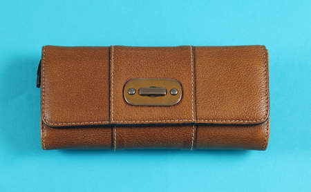 Closed expensive brown leather wallet  fashion accessory isolated on blue backgroundの写真素材