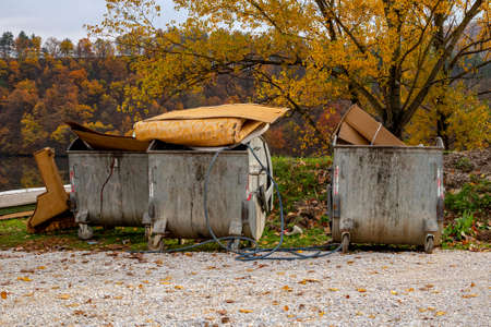 Open metal trash bins with used furniture and other household items thrown awayの写真素材