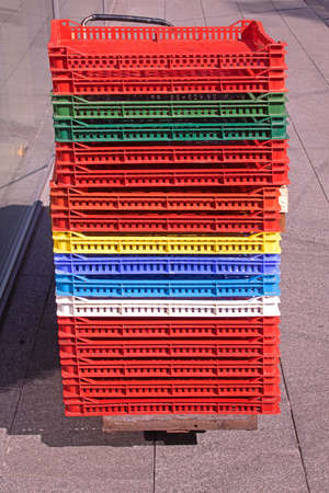 Colorful plastic crates folded in stack sold on market