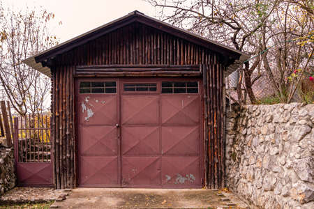 Retro wooden shed with closed metal door outside in countryside
