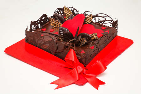 Chocolate cake with heart decoration and tied bow on red trayの写真素材