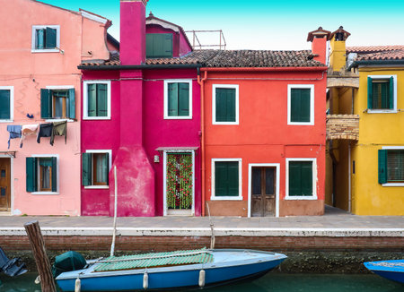 Retro houses with colorful facades on canal in Burano island with boats in waterの写真素材