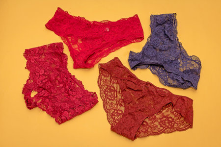 Colorful lace material female knickers underwear isolated on yellow backgroundの写真素材