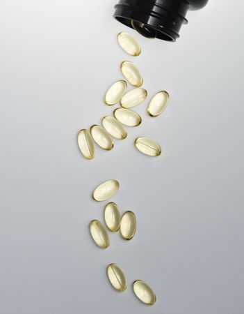 Vitamin E pills spill out on a gray surface