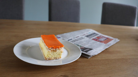 Orange cake and newspaper on a wooden table. Selective focus, Tompoes, tompouce, typical dutch cake, queensday, kingsday, puff pastry and pastry creamの写真素材