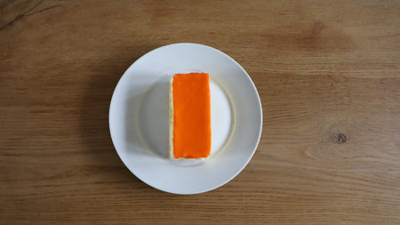 Orange cake on white plate on wooden table. Top view, flat lay, Tompoes, tompouce, typical dutch cake, queensday, kingsday, puff pastry and pastry creamの写真素材