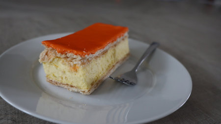 Orange cake on a white plate with a spoon in the background, Tompoes, tompouce, typical dutch cake, queensday, kingsday, puff pastry and pastry creamの写真素材