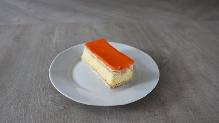 Orange cake on a white plate on a gray background. copy-space. , Tompoes, tompouce, typical dutch cake, queensday, kingsday, puff pastry and pastry creamの写真素材