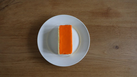 Orange cake on white dish on wooden table. Top view with copy space. , Tompoes, tompouce, typical dutch cake, queensday, kingsday, puff pastry and pastry creamの写真素材