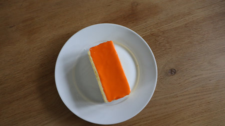 Orange cake on white dish on wooden table. Top view with copy space. Tompoes, tompouce, typical dutch cake, queensday, kingsday, puff pastry and pastry creamの写真素材