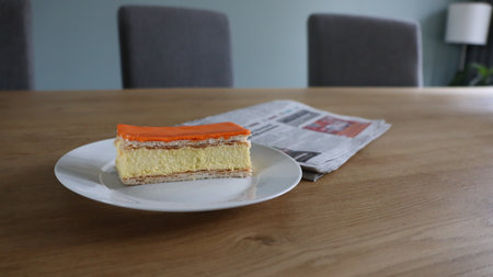 Orange cake with newspaper on the table in coffee shop, stock photo, Tompoes, tompouce, typical dutch cake, queensday, Koningsdag, puff pastry and pastry creamの写真素材