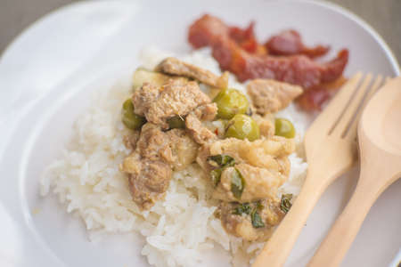 green curry pork and fried pork with cooked rice on wood tableの写真素材