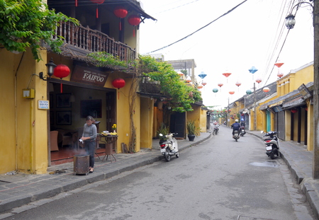 HOI AN, VIETNAM - 17TH MARCH 2018: Woman praying and burning papers for good business in front of restaurant in Hoi Anのeditorial素材